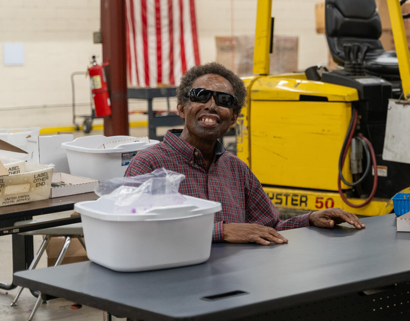 Ray, a man wearing dark glasses, working in the BDI warehouse. Ray lost his vision more than 40 years ago, he is in his senior years. BDI is providing him the opportunity to work. Ray is one BDI's most productive employees.