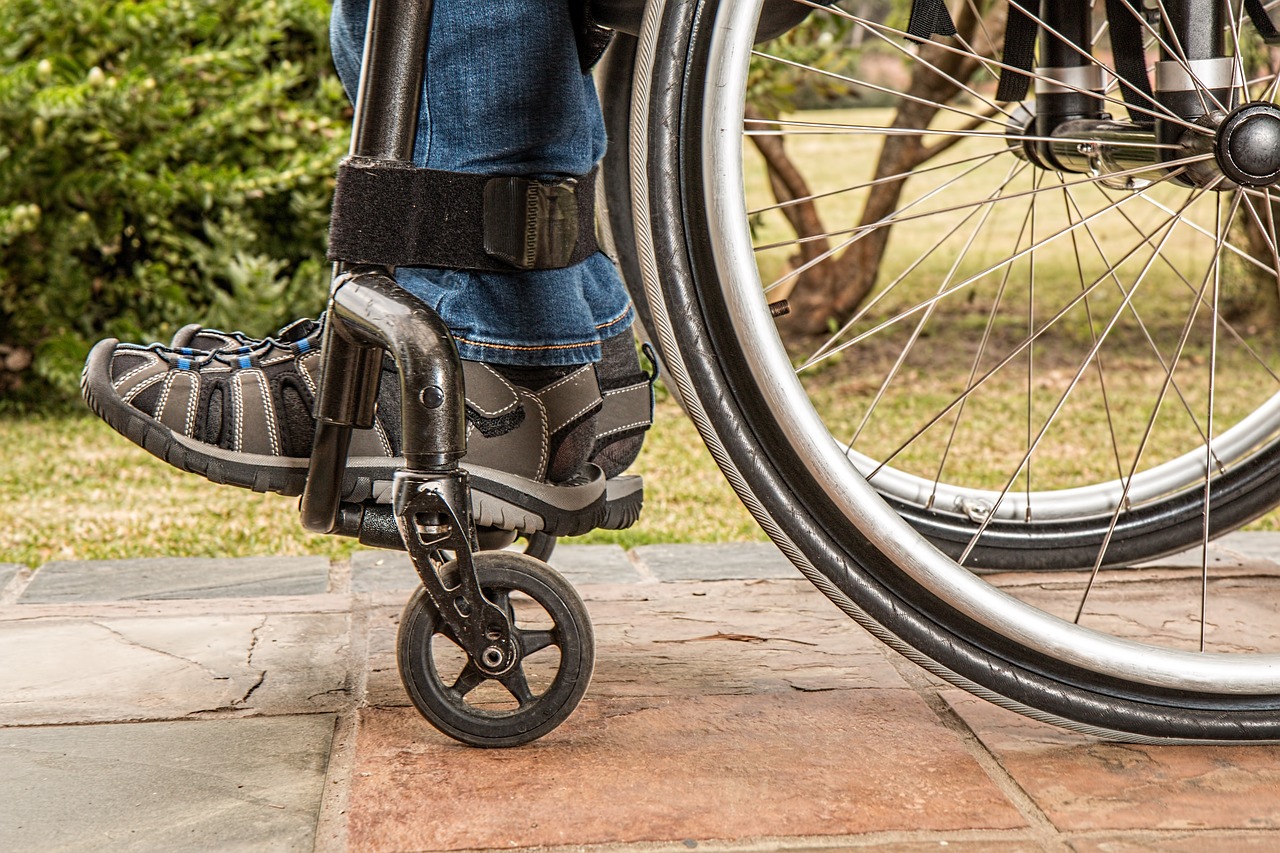 A close-up of the wheels of a wheelchair being used by a person.
