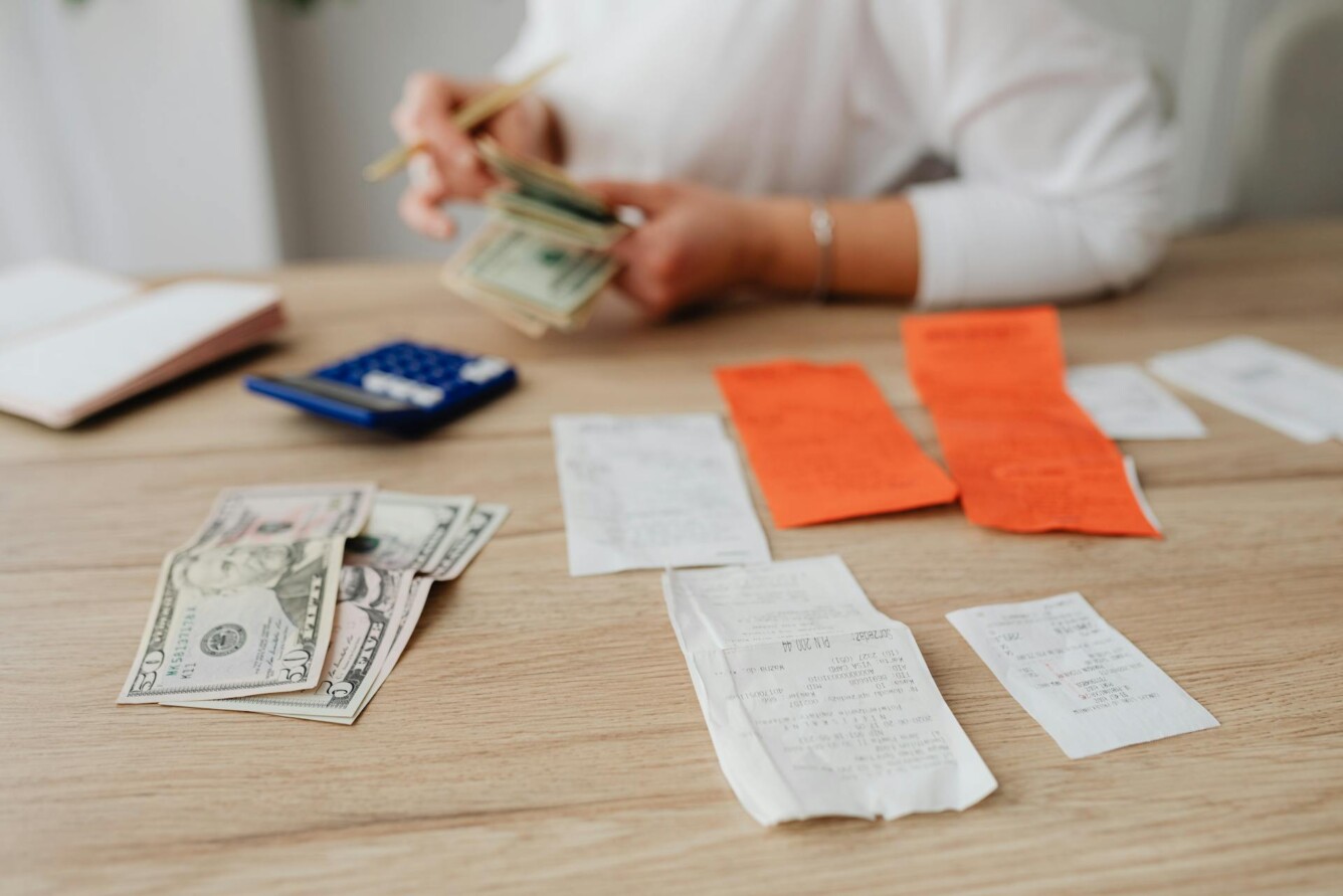 A person organizing money and receipts at a table, with a calculator and a notebook nearby.