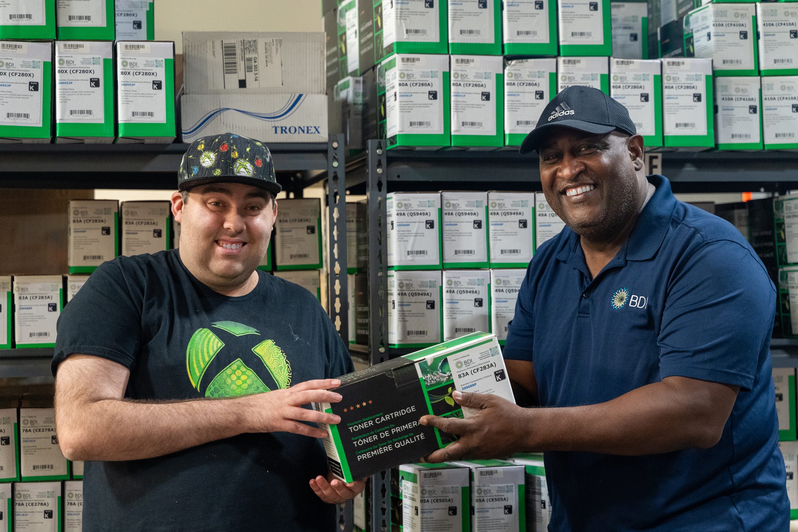 Two BDI Warehouse employees holding a Toner Cartridge box. For one of BDI contracts, the team labels the boxes for our client