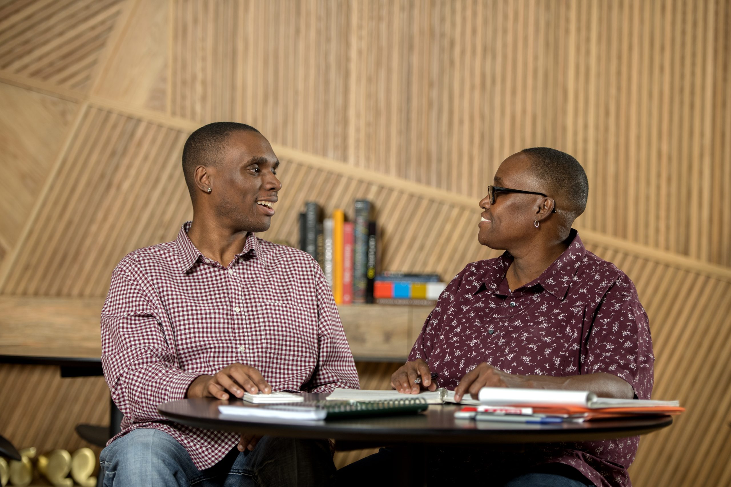 Roderick, a participant in the BDI service, sitting at a table with documents, alongside his mom, Jackie.