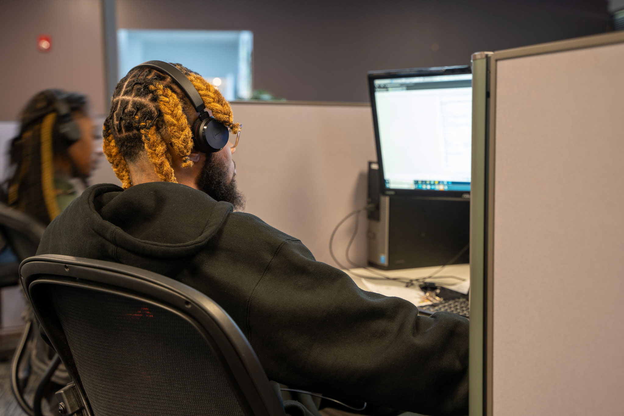 A contact center agent at the BDI facility taking a call. The person is wearing a headset and looking at the a computer monitor.