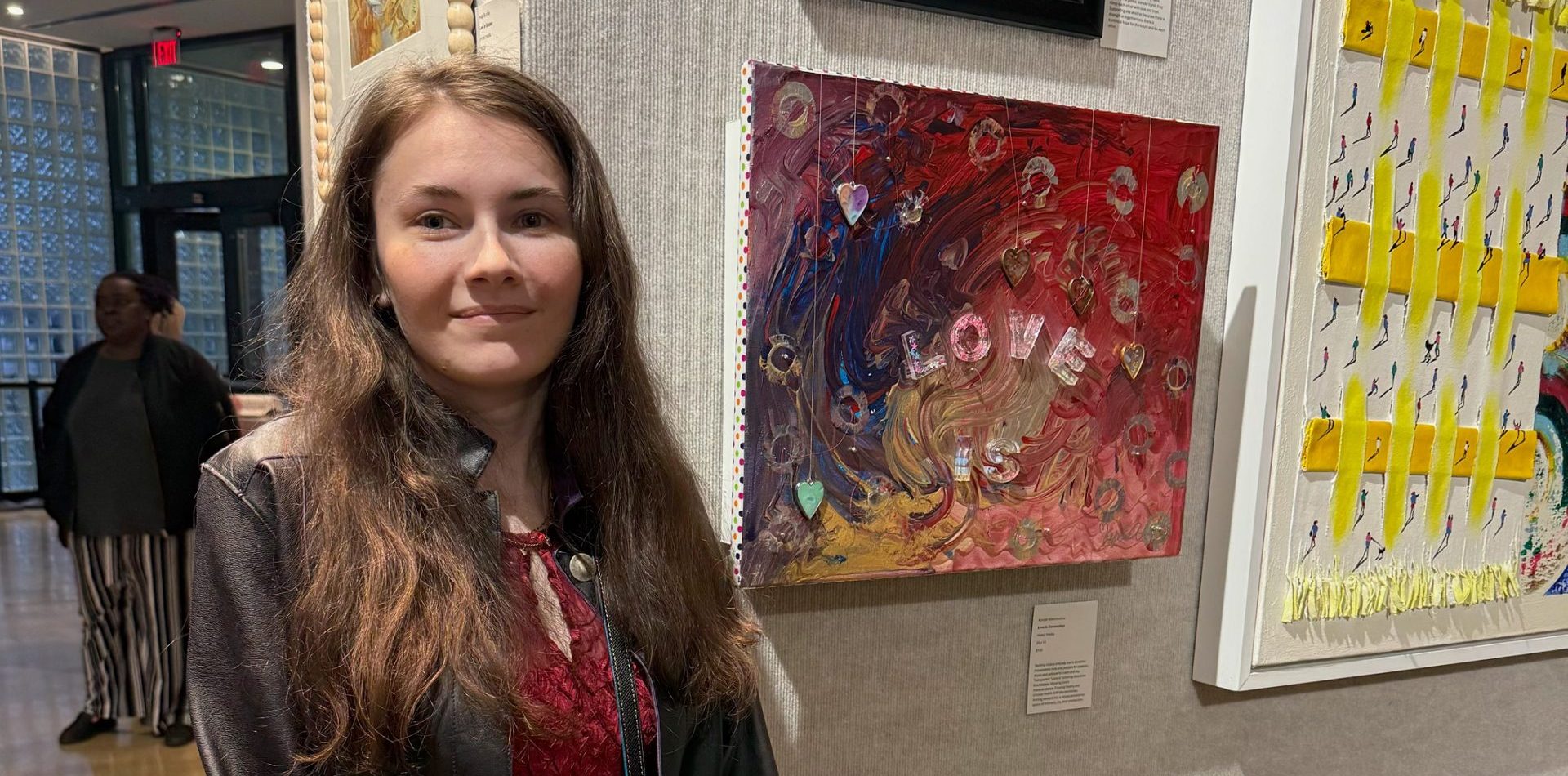 Kyndel poses for a photo in a gallery with one of her abstract paintings.
